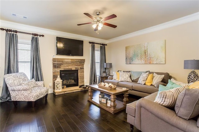 living room featuring ceiling fan, ornamental molding, hardwood / wood-style floors, and a stone fireplace