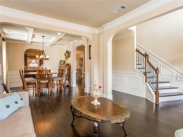 living room featuring dark hardwood / wood-style flooring, coffered ceiling, ornamental molding, beam ceiling, and an inviting chandelier