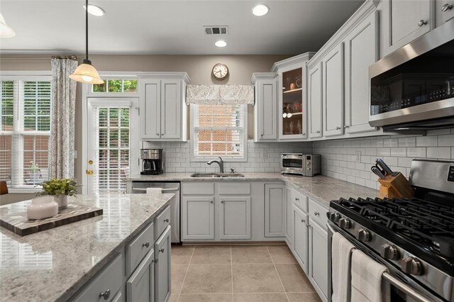 2303 Waters Edge Trl, Roswell, GA 30075 - kitchen featuring appliances with stainless steel finishes, a sink, light tile patterned floors, tasteful backsplash, and glass insert cabinets