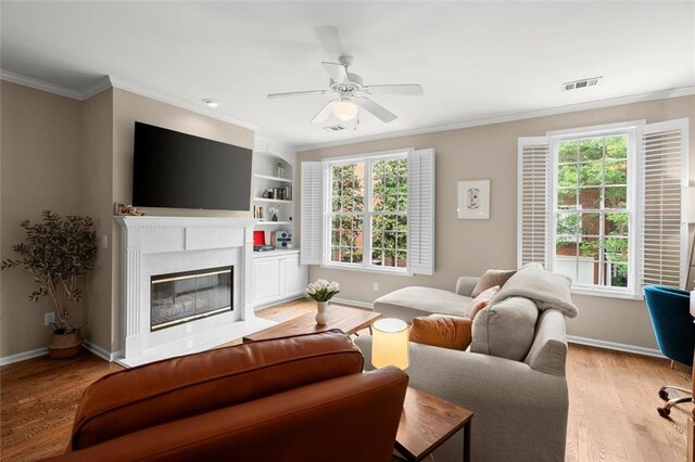 2303 Waters Edge Trl, Roswell, GA 30075 - living room with crown molding, plenty of natural light, baseboards, light wood-style flooring, and a fireplace with flush hearth