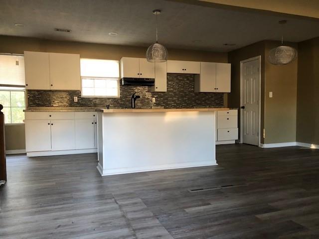 kitchen featuring white cabinetry, decorative backsplash, and hanging light fixtures