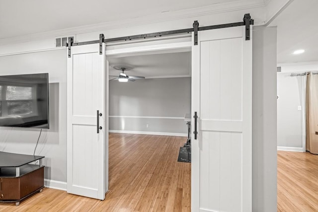 interior space with wood-type flooring, a barn door, and crown molding