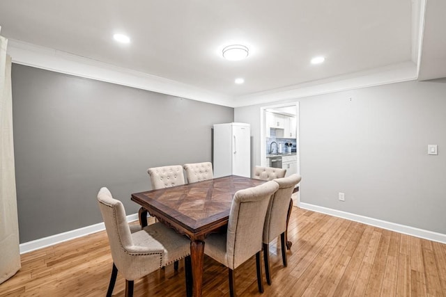 dining room featuring crown molding, sink, and light wood-type flooring