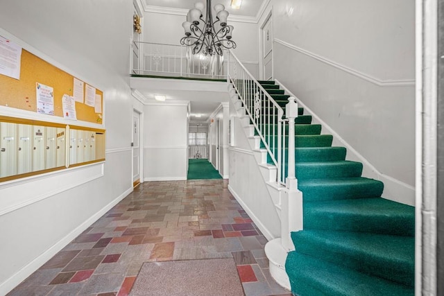 staircase featuring mail boxes, ornamental molding, a towering ceiling, and a chandelier