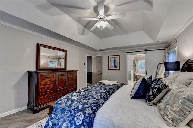 127 Bradshaw Park Dr, Woodstock, GA 30188 - bedroom featuring a raised ceiling, wood finished floors, a barn door, ceiling fan, and connected bathroom
