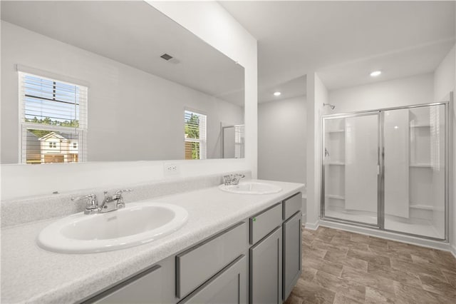 bathroom featuring a shower stall, double vanity, visible vents, and a sink