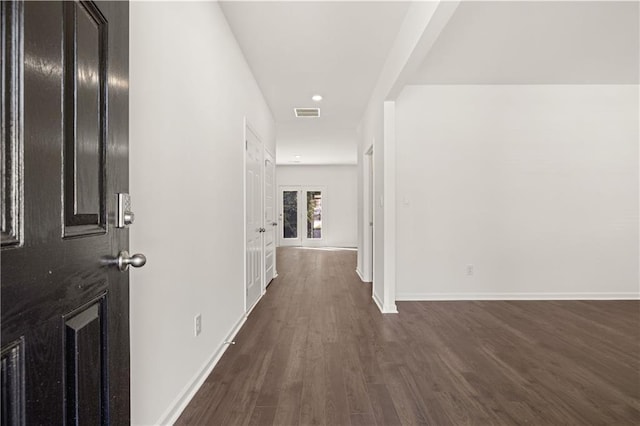 hallway featuring dark wood-style floors, baseboards, and visible vents