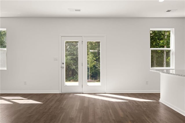 spare room with baseboards, visible vents, and wood finished floors