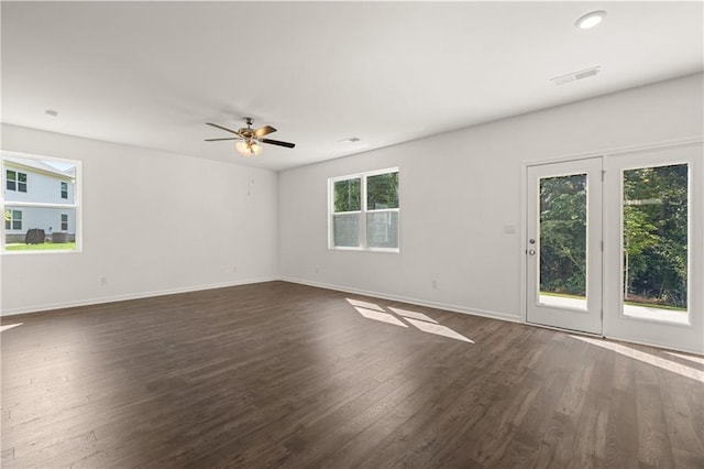 empty room with baseboards, dark wood-style flooring, ceiling fan, and visible vents