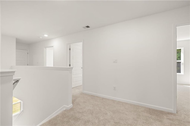 corridor with baseboards, an upstairs landing, visible vents, and light carpet