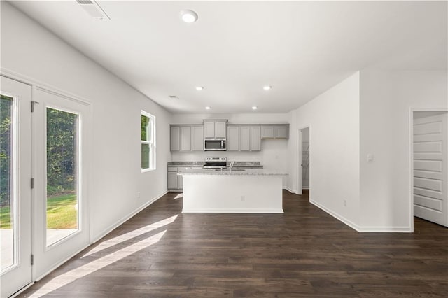 kitchen featuring an island with sink, dark wood-style floors, gray cabinetry, stainless steel appliances, and recessed lighting