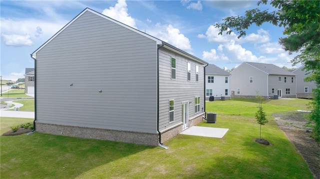 view of side of home with a patio, central AC, and a yard