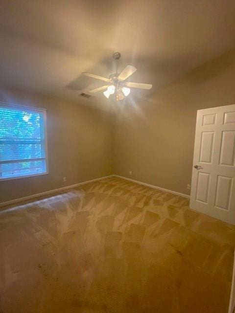 unfurnished room featuring carpet floors, a ceiling fan, visible vents, vaulted ceiling, and baseboards