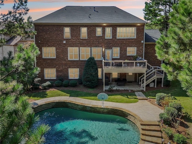 back house at dusk featuring a patio area and a pool side deck