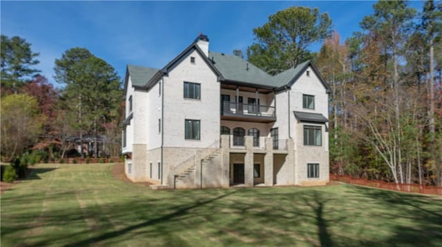 back of property featuring a lawn, a chimney, and a balcony