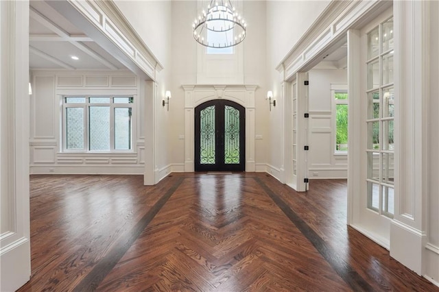 foyer entrance with baseboards, a high ceiling, french doors, parquet flooring, and a notable chandelier