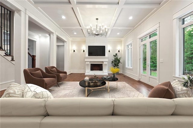 living room featuring dark wood-style flooring, crown molding, a fireplace, an inviting chandelier, and coffered ceiling