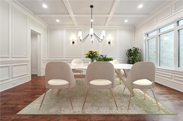 dining area with coffered ceiling, a chandelier, a decorative wall, and dark wood finished floors