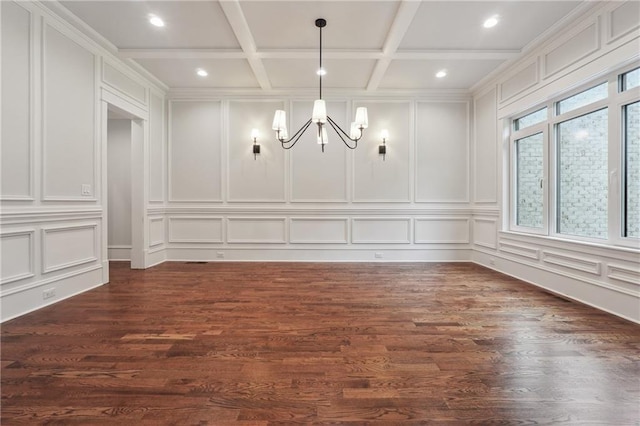 unfurnished dining area with dark wood-style floors, a decorative wall, a notable chandelier, and coffered ceiling