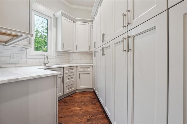 kitchen with tasteful backsplash, a sink, light stone counters, and white cabinetry