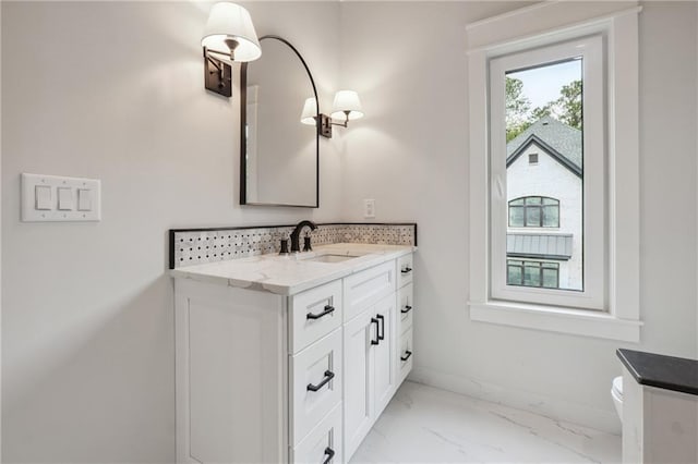 bathroom featuring toilet, marble finish floor, baseboards, and vanity