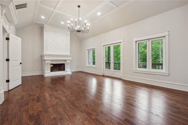 unfurnished living room with a notable chandelier, a fireplace, lofted ceiling, visible vents, and wood finished floors