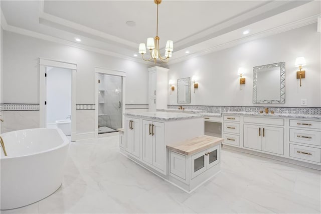 bathroom with marble finish floor, double vanity, a raised ceiling, ornamental molding, and a shower stall