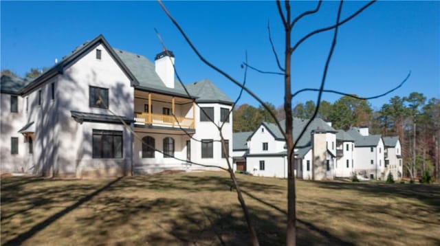 rear view of house with a yard, a chimney, a residential view, and a balcony