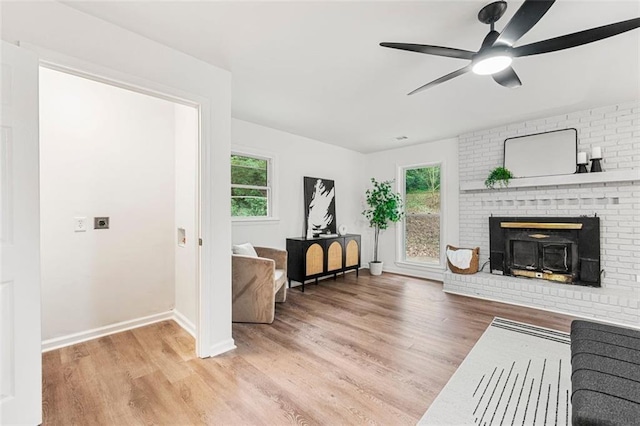 living area featuring baseboards, a fireplace, a ceiling fan, and wood finished floors