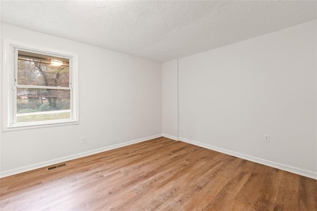 unfurnished room featuring visible vents, baseboards, a textured ceiling, and wood finished floors