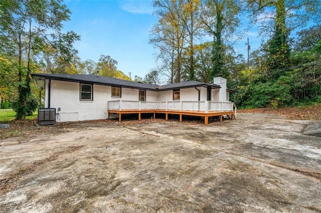 rear view of property featuring central AC, a chimney, and a deck