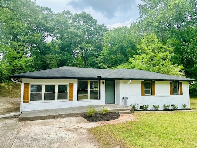 view of front of house featuring covered porch, brick siding, roof with shingles, and a front lawn