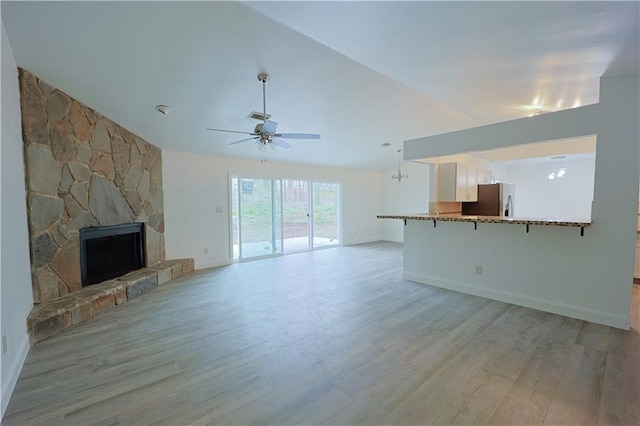 unfurnished living room with lofted ceiling, a fireplace, light hardwood / wood-style floors, and ceiling fan