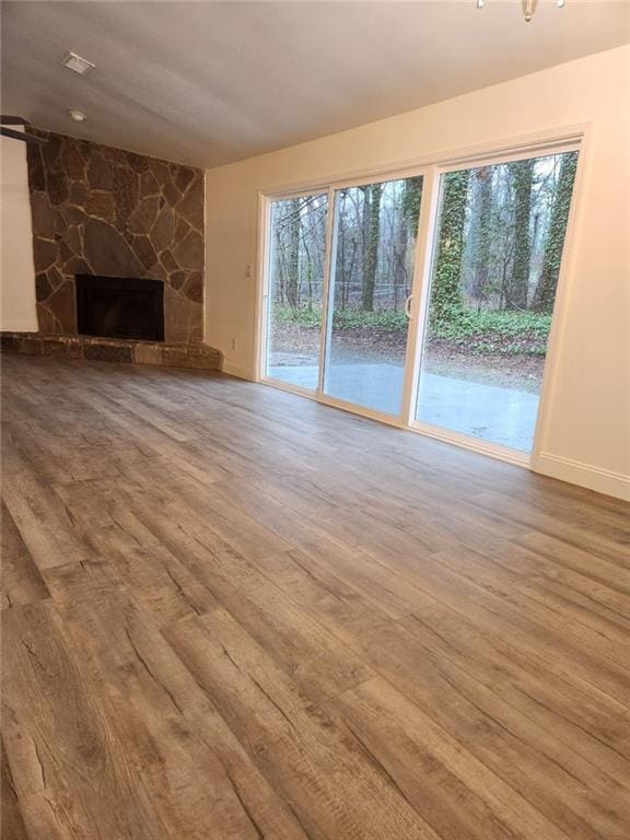 unfurnished living room featuring a stone fireplace and hardwood / wood-style floors