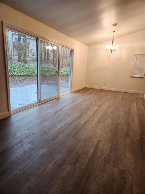 spare room with an inviting chandelier, vaulted ceiling, and dark hardwood / wood-style floors