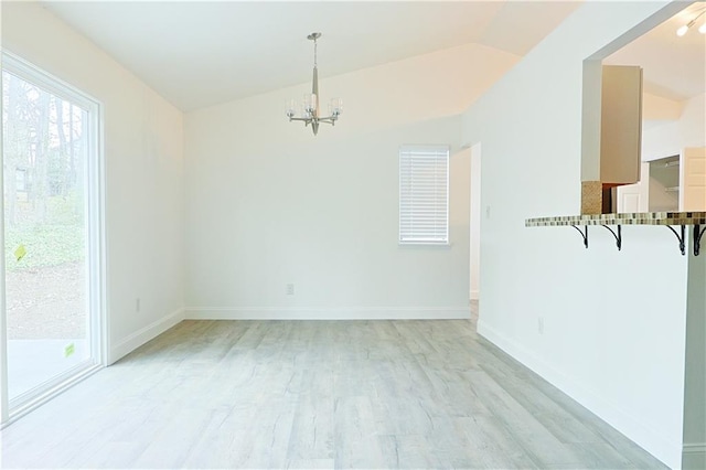 empty room featuring vaulted ceiling, light wood-type flooring, and a chandelier