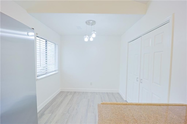 empty room with light hardwood / wood-style flooring and a chandelier