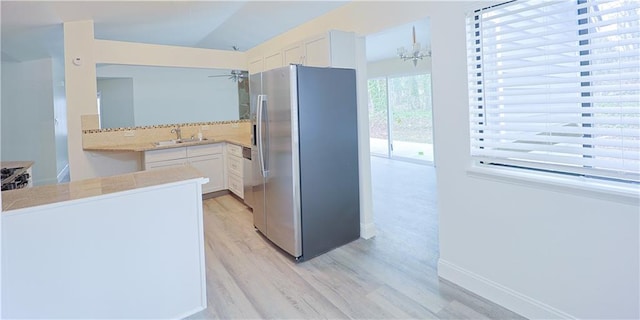 kitchen with white cabinetry, sink, kitchen peninsula, and stainless steel fridge with ice dispenser