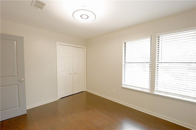 unfurnished bedroom with dark hardwood / wood-style floors and a closet