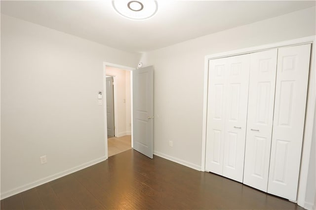 unfurnished bedroom featuring dark hardwood / wood-style floors and a closet