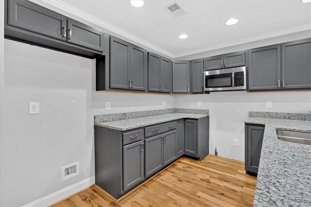 kitchen featuring visible vents, appliances with stainless steel finishes, a peninsula, crown molding, and a sink