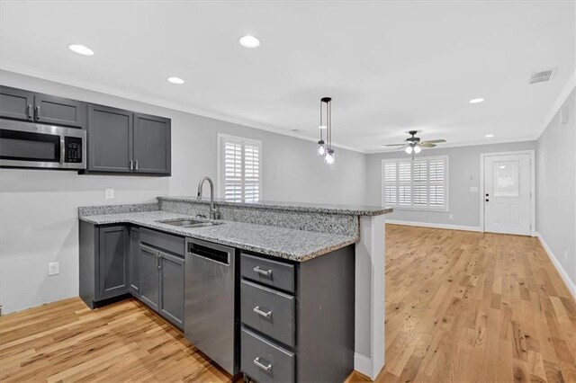 kitchen featuring a sink, crown molding, stainless steel dishwasher, and gray cabinetry