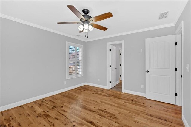 empty room with ornamental molding, a ceiling fan, baseboards, and wood finished floors