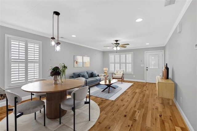 dining room featuring ornamental molding, light wood-type flooring, visible vents, and baseboards