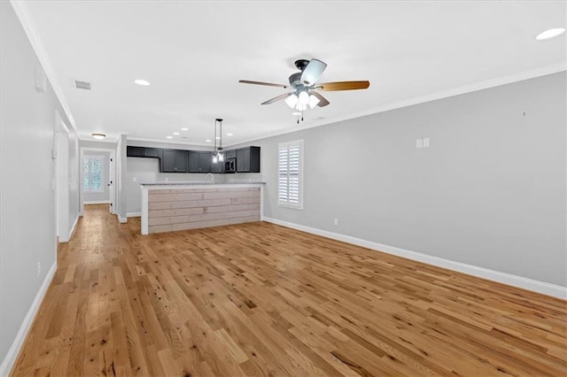 unfurnished living room featuring light wood-type flooring, visible vents, crown molding, and baseboards