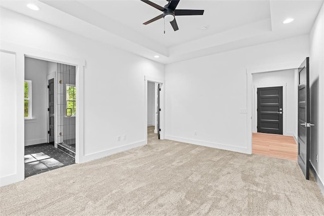 unfurnished living room featuring ceiling fan, a raised ceiling, and carpet floors