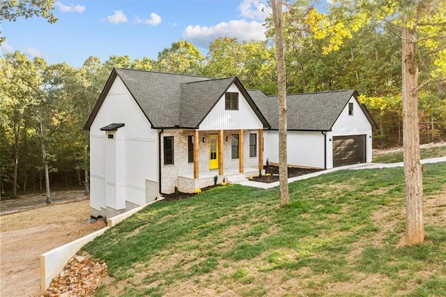 modern inspired farmhouse featuring covered porch, a front yard, and a garage