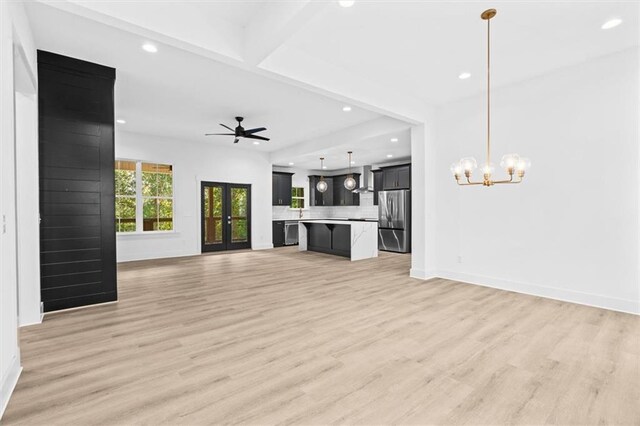 unfurnished living room featuring light hardwood / wood-style flooring and ceiling fan with notable chandelier