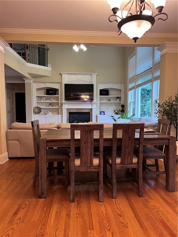 dining area featuring a fireplace, hardwood / wood-style floors, an inviting chandelier, and ornamental molding