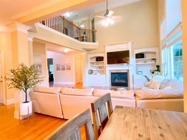 living room with wood-type flooring, high vaulted ceiling, ceiling fan, and ornamental molding